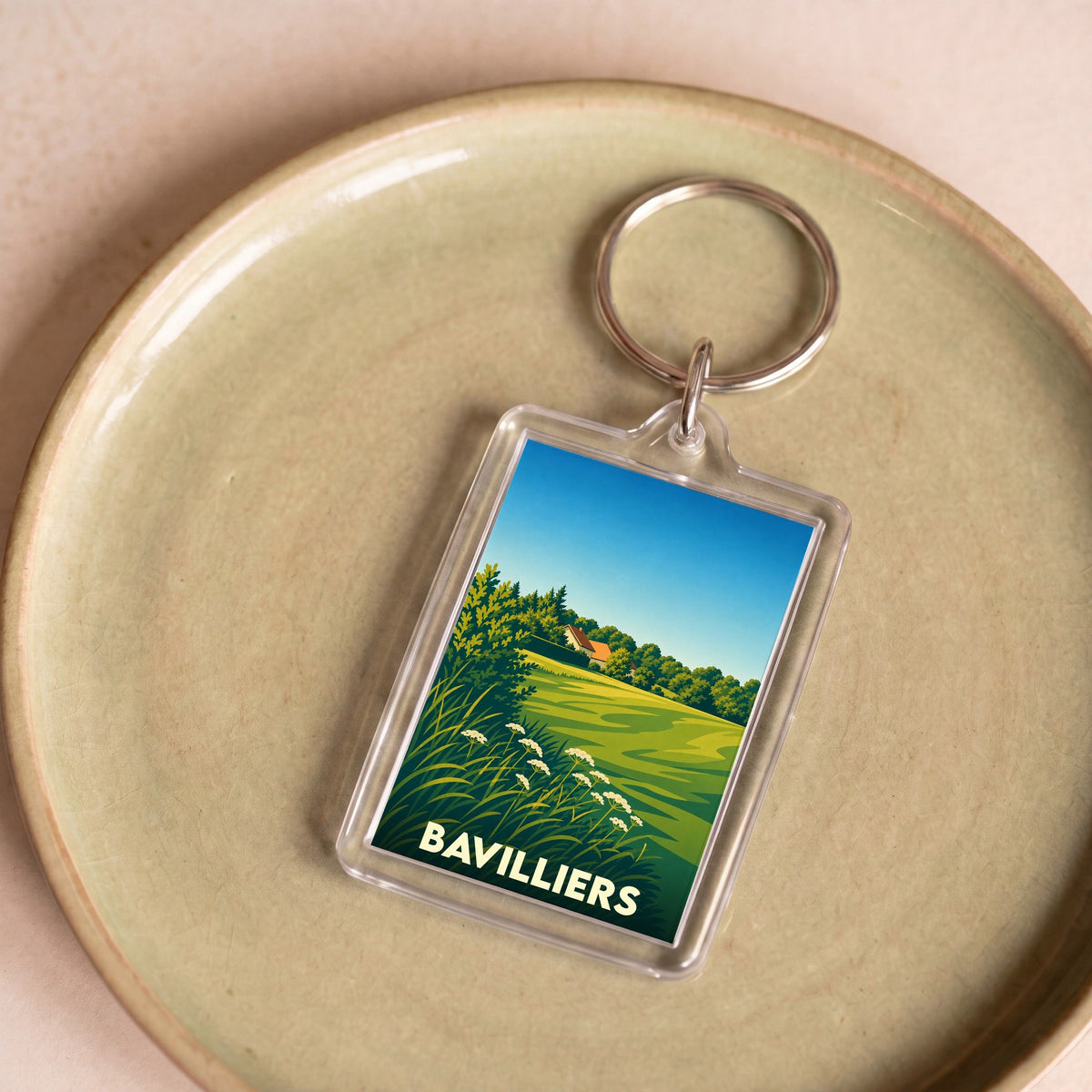 Porte-clés souvenir de la ville de Bavilliers avec une illustration de paysage champêtre.