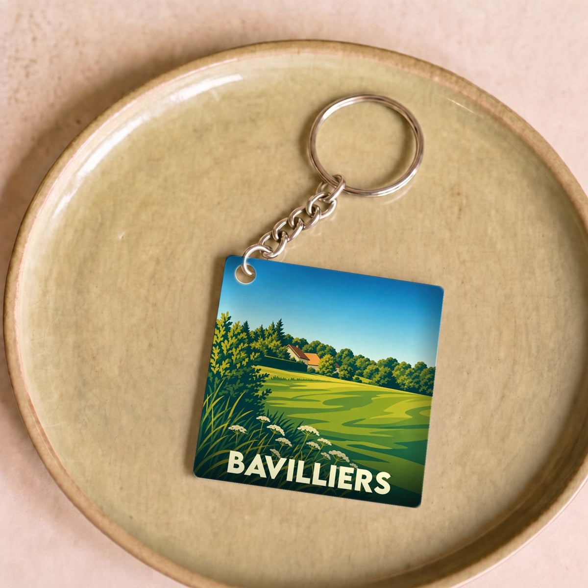 Porte-clés souvenir de la ville de Bavilliers avec une illustration paysagère stylisée.