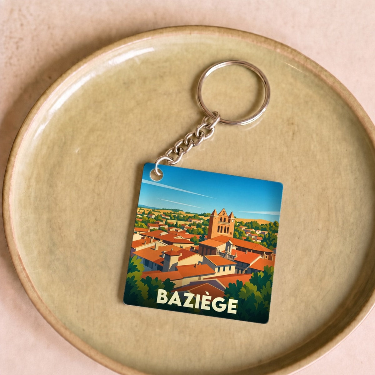Porte-clés souvenir de la ville de Baziège avec une illustration stylisée.