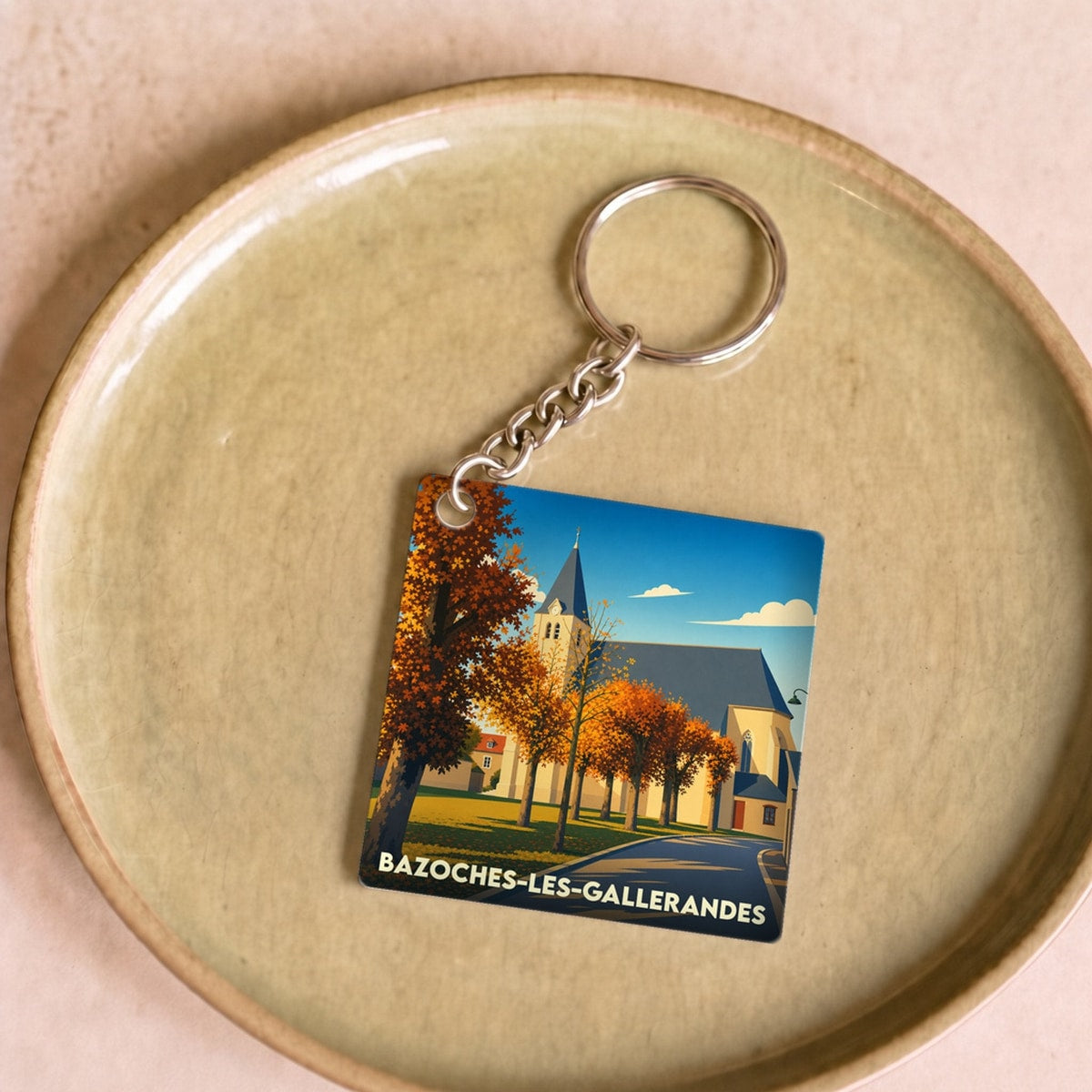 Porte-clés souvenir de la ville de Bazoches-les-Gallerandes avec une illustration stylisée de son église en automne.