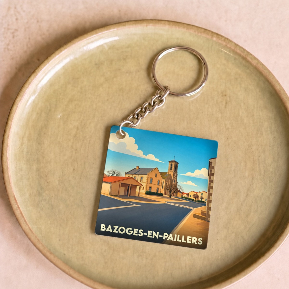 Porte-clés souvenir de la ville de Bazoges-en-Paillers avec une illustration stylisée.