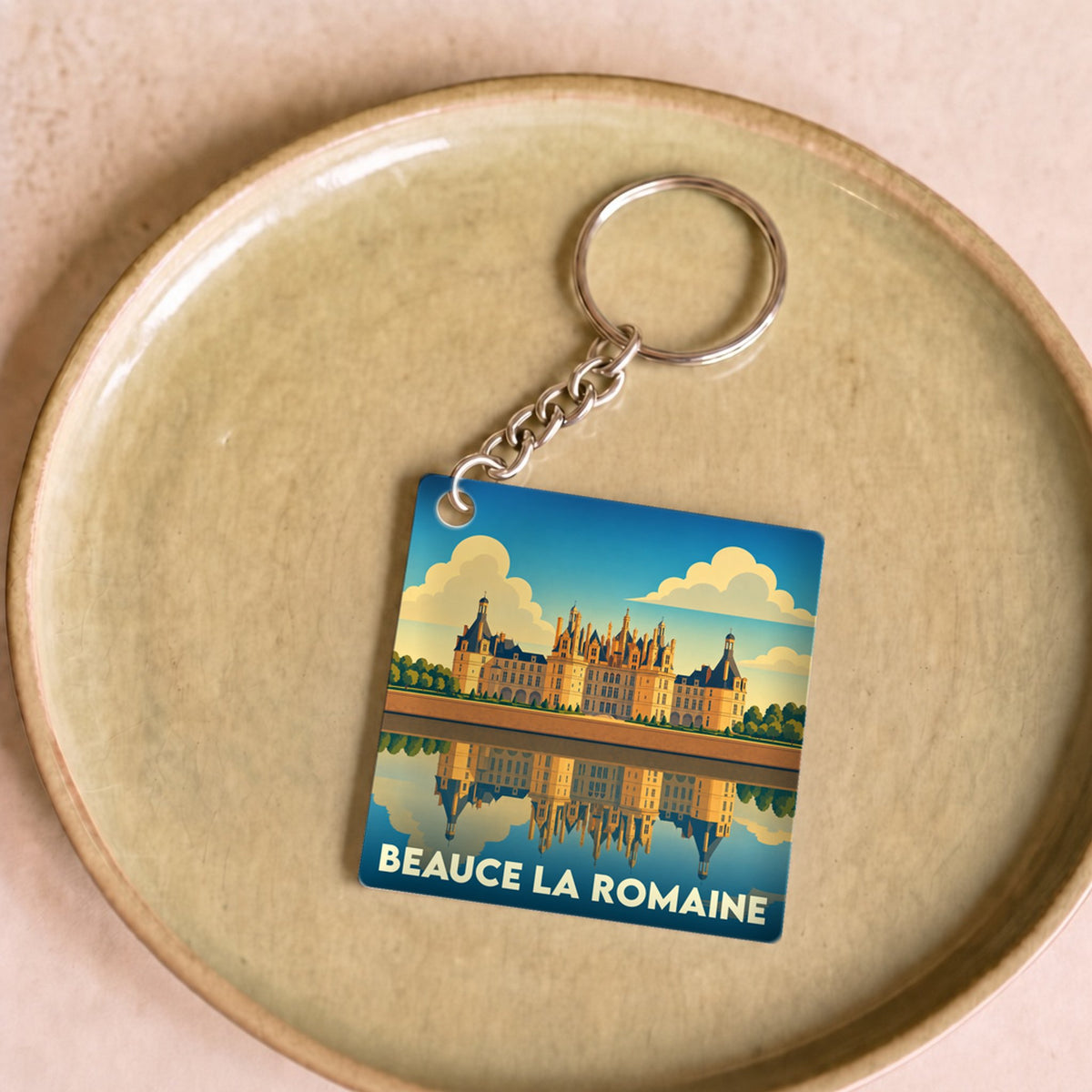 Porte-clés souvenir de la ville de Beauce la Romaine illustré par un château se reflétant sur l'eau.