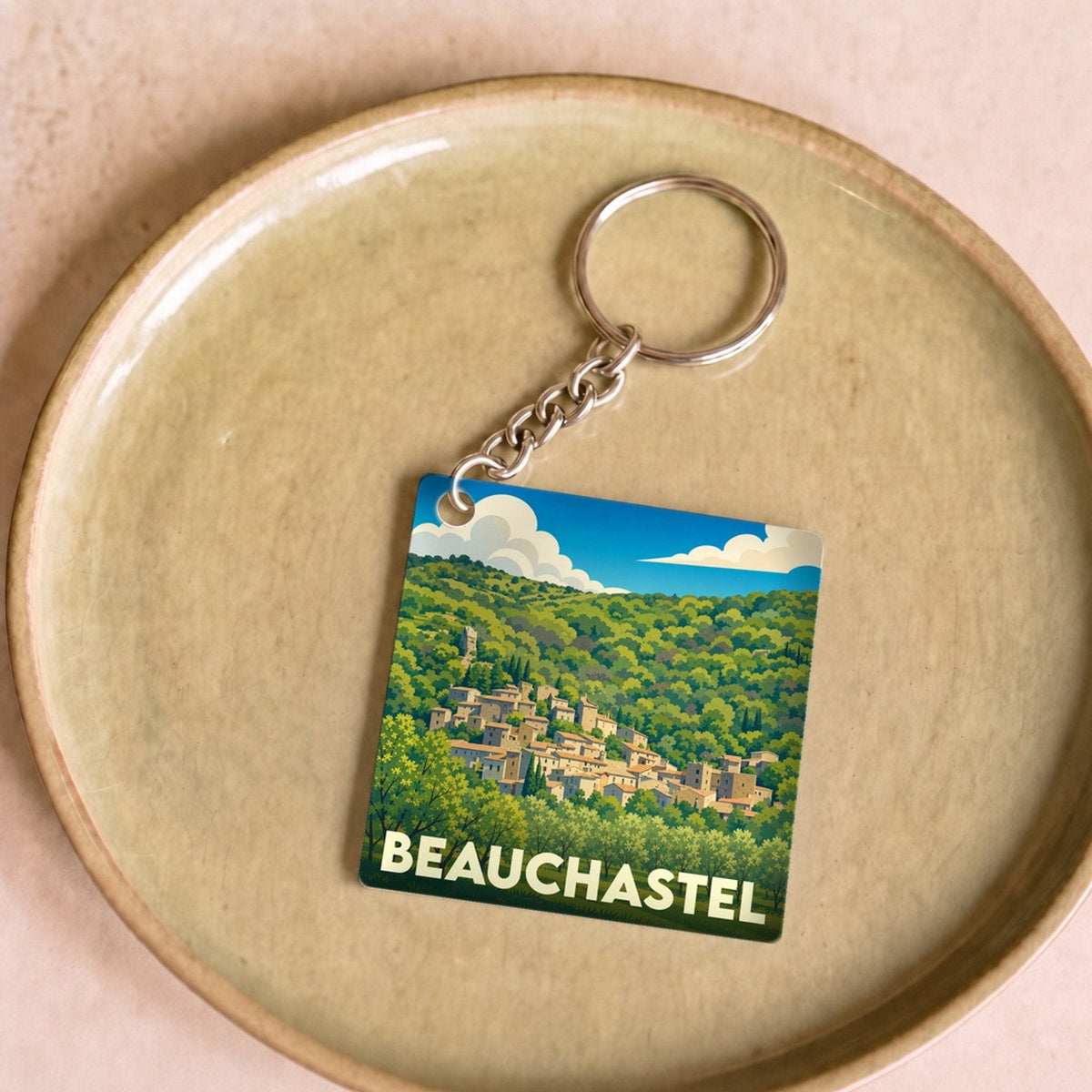Porte-clés souvenir de la ville de Beauchastel avec une illustration stylisée d'un village perché.