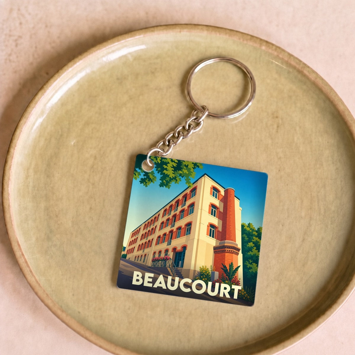 Porte-clés souvenir de la ville de Beaucourt avec une illustration stylisée.