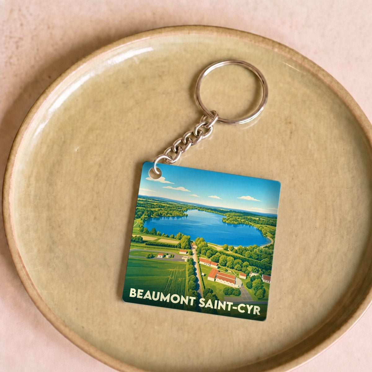 Porte-clés souvenir de la ville de Beaumont Saint-Cyr avec une illustration stylisée d'un paysage aérien.