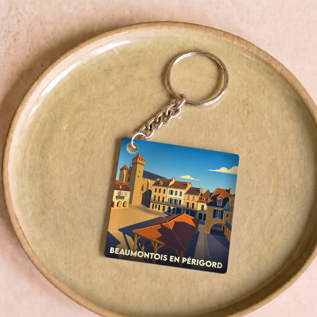 Porte-clés souvenir de Beaumontois en Périgord avec une illustration stylisée de sa place centrale.