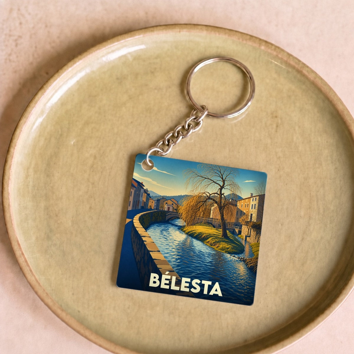 Porte-clés souvenir de la ville de Bélesta avec une illustration stylisée d'un canal et de son saule pleureur.