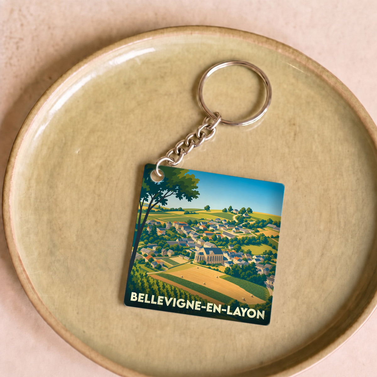 Porte-clés souvenir de la ville de Bellevigne-en-Layon avec une illustration stylisée de son paysage rural.