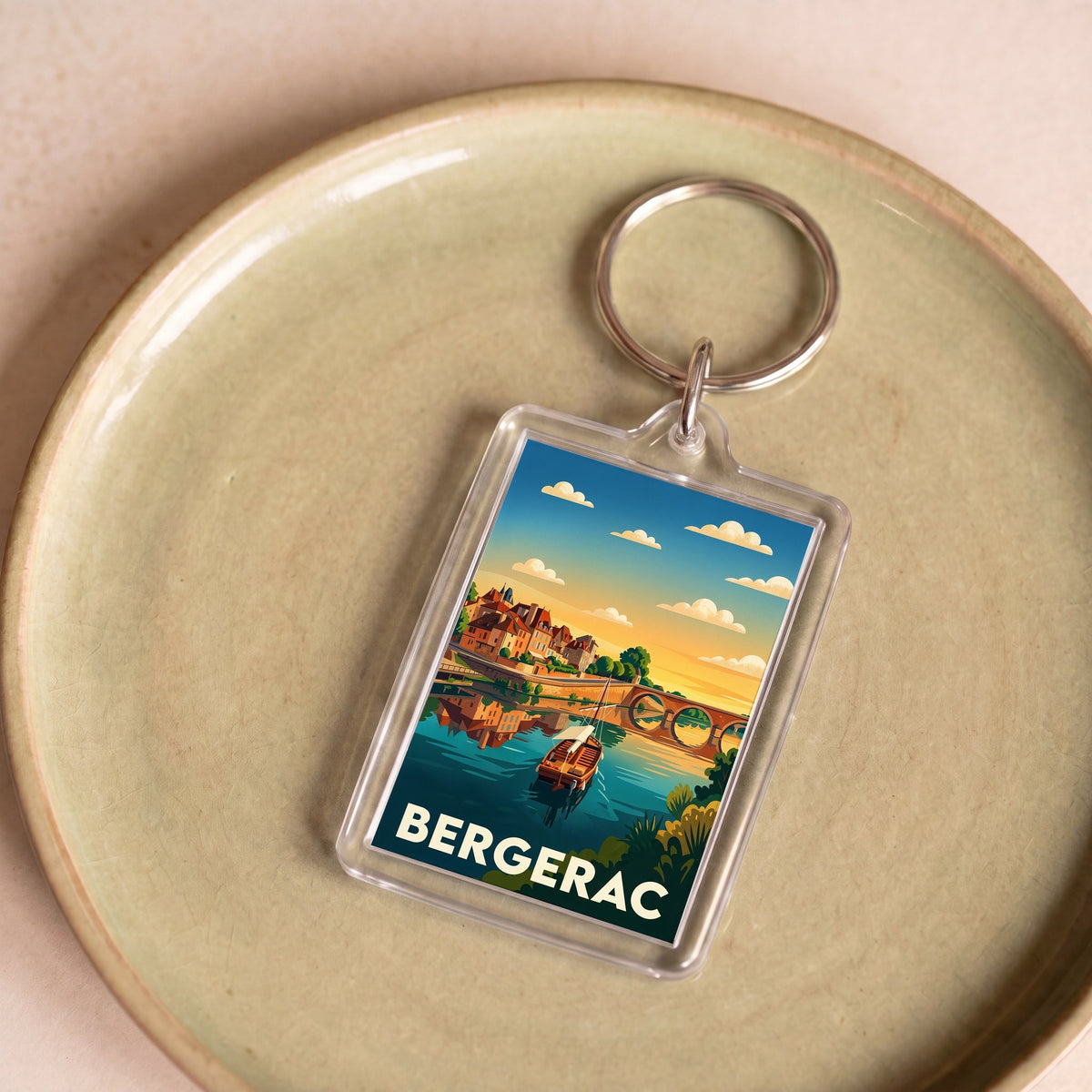 Porte-clés souvenir de la ville de Bergerac avec une illustration stylisée de son paysage fluvial.