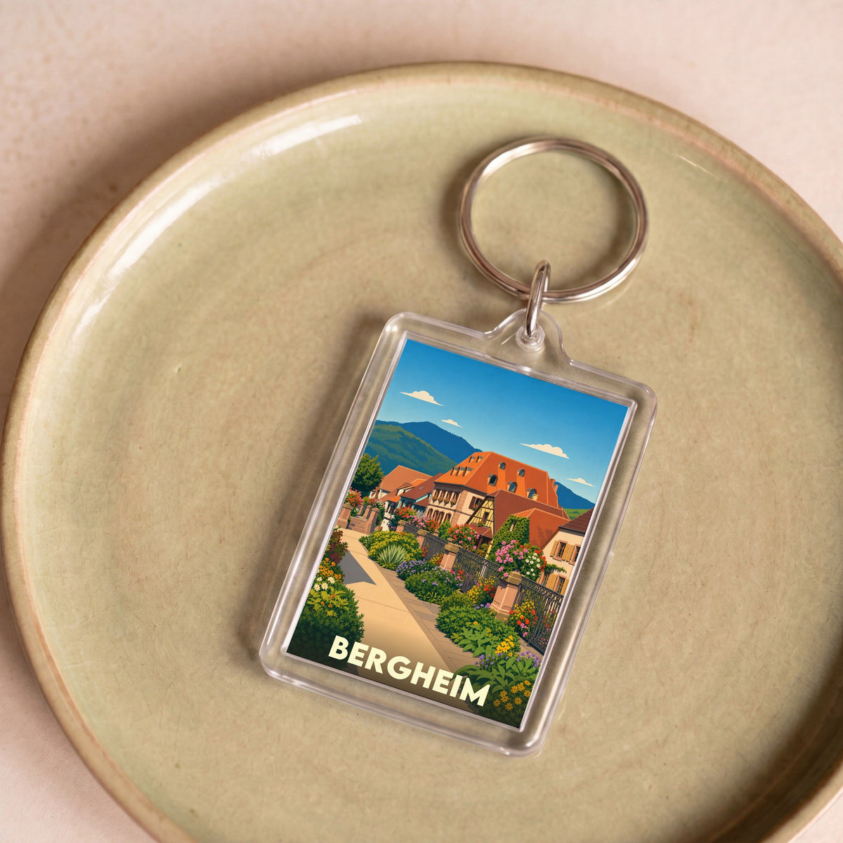 Porte-clés souvenir de la ville de Bergheim avec une illustration stylisée d'une ruelle fleurie et de maisons traditionnelles.