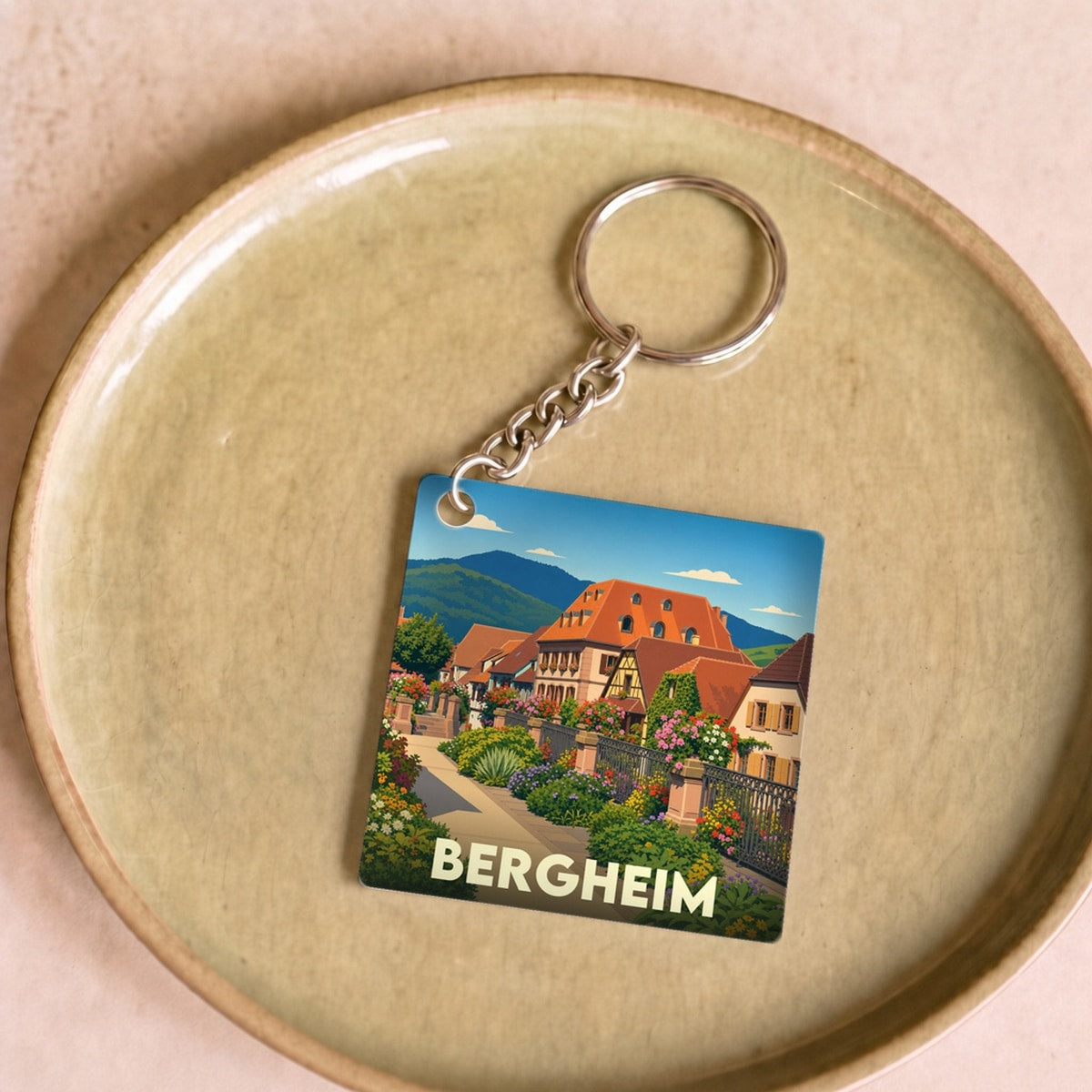 Porte-clés souvenir de la ville de Bergheim avec une illustration stylisée d'une ruelle fleurie et de maisons traditionnelles.