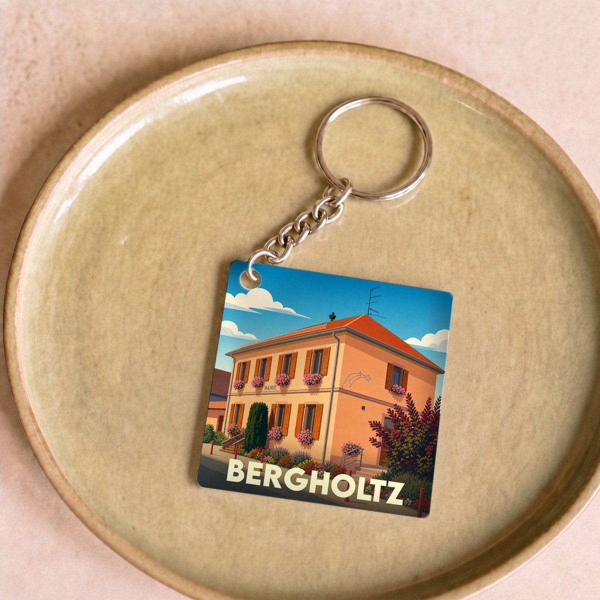 Porte-clés souvenir de la ville de Bergholtz avec une illustration stylisée de la mairie.