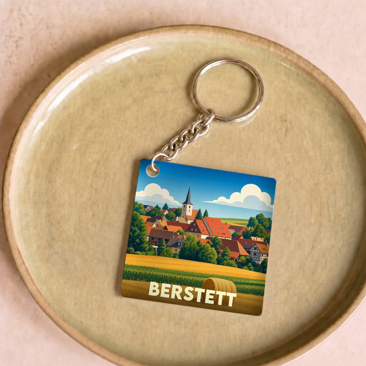 Porte-clés souvenir de la ville de Berstett avec une illustration stylisée d'un paysage alsacien.