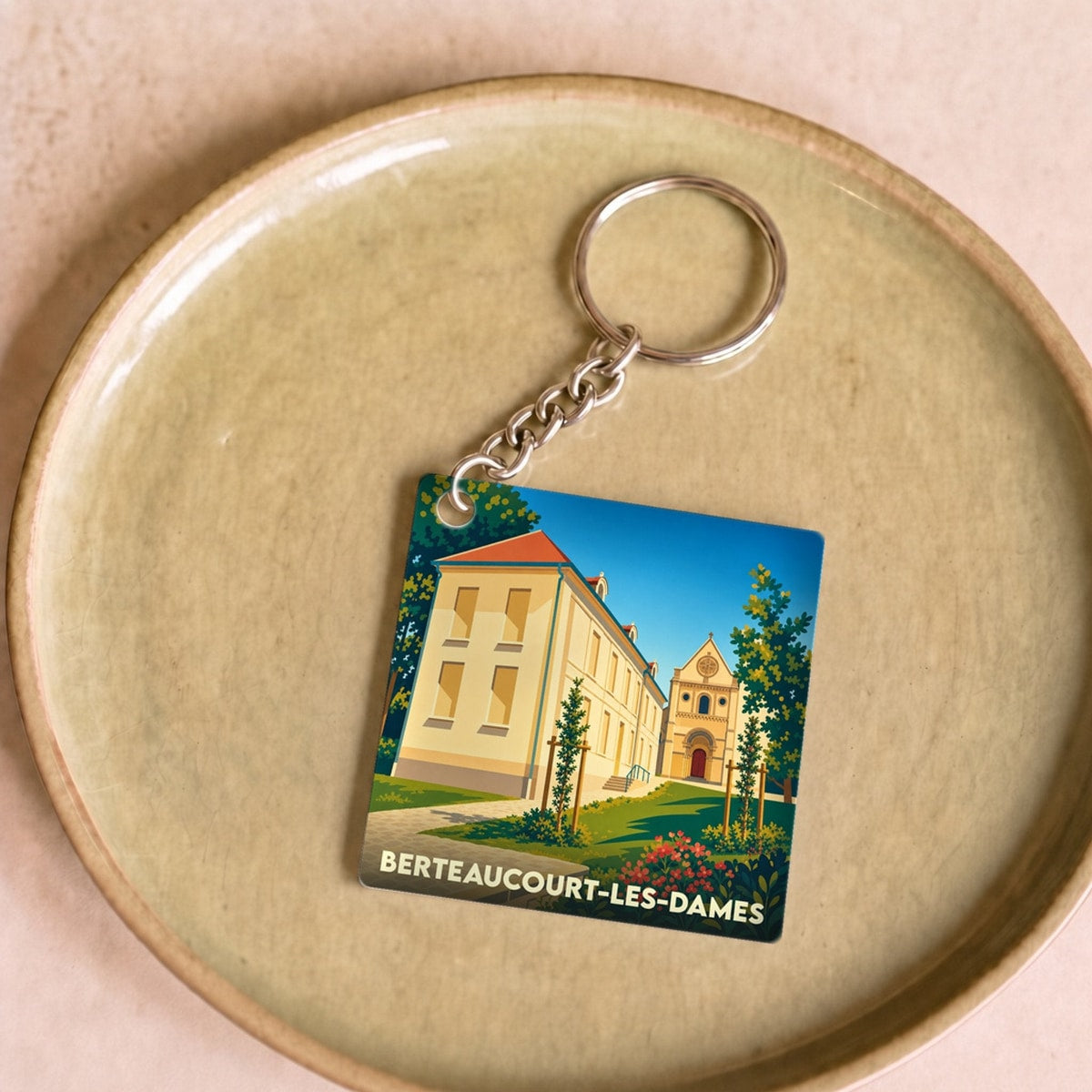 Porte-clés souvenir de la ville de Berteaucourt-les-Dames avec une illustration stylisée.