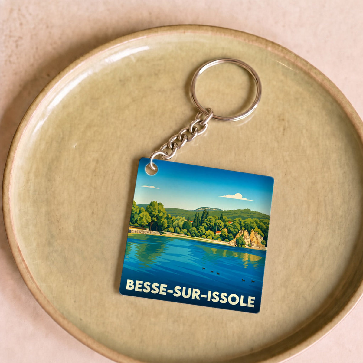 Porte-clés souvenir de la ville de Besse-sur-Issole avec une illustration stylisée d'un lac bordé de verdure.