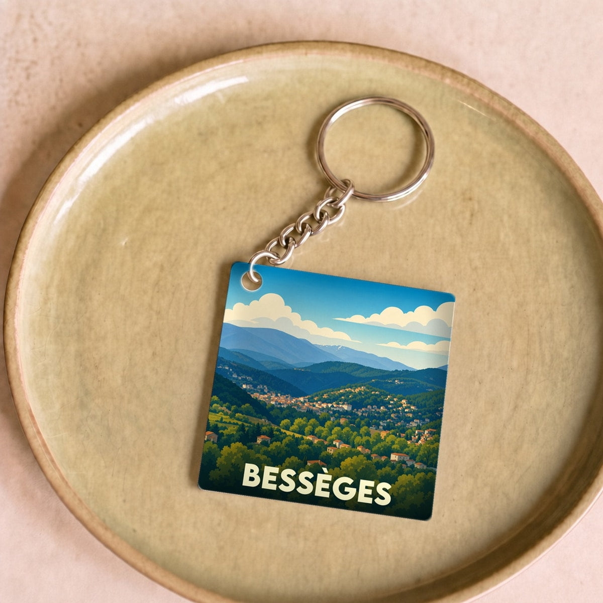 Porte-clés souvenir de la ville de Bessèges avec une illustration stylisée de son paysage vallonné.