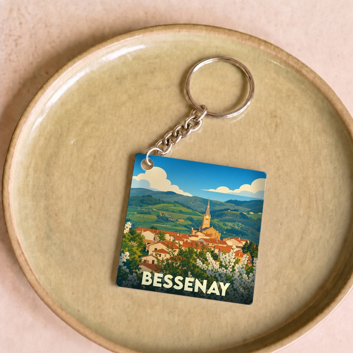Porte-clés souvenir de la ville de Bessenay avec une illustration stylisée de son paysage vallonné.