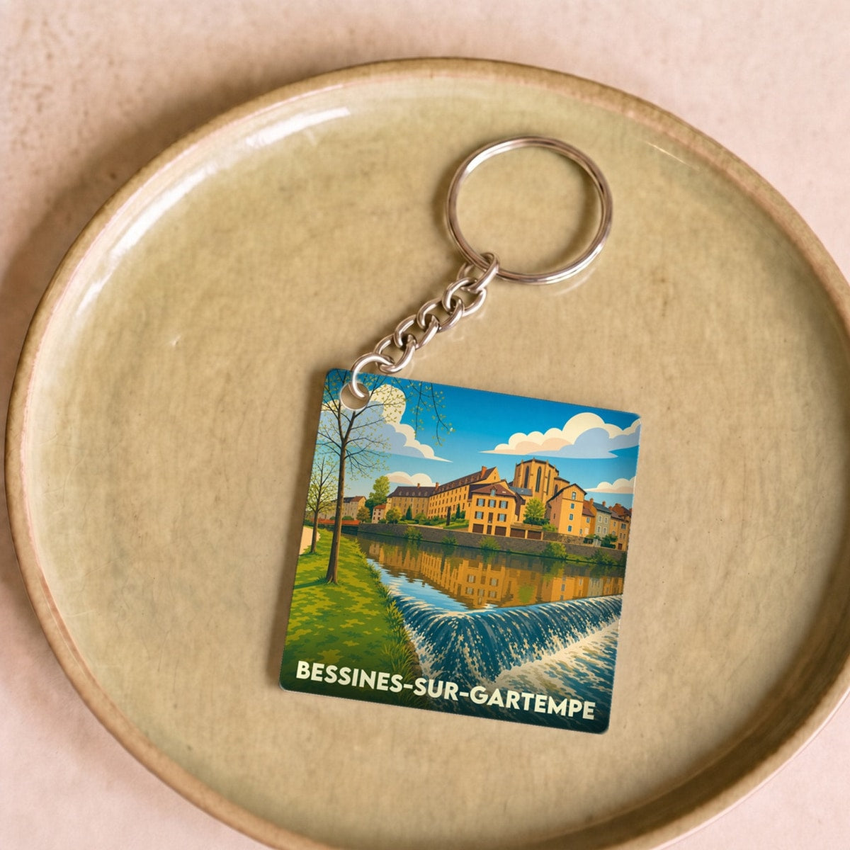 Porte-clés souvenir de Bessines-sur-Gartempe avec une illustration stylisée de la ville au bord de l'eau.