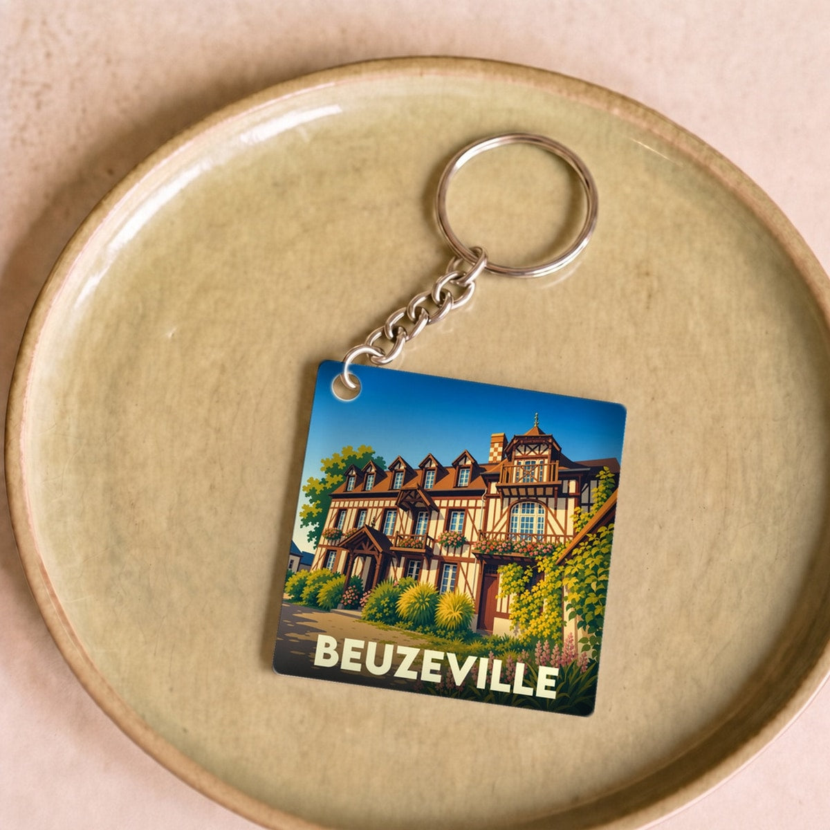 Porte-clés souvenir de la ville de Beuzeville avec une illustration stylisée d'une maison normande à colombages.