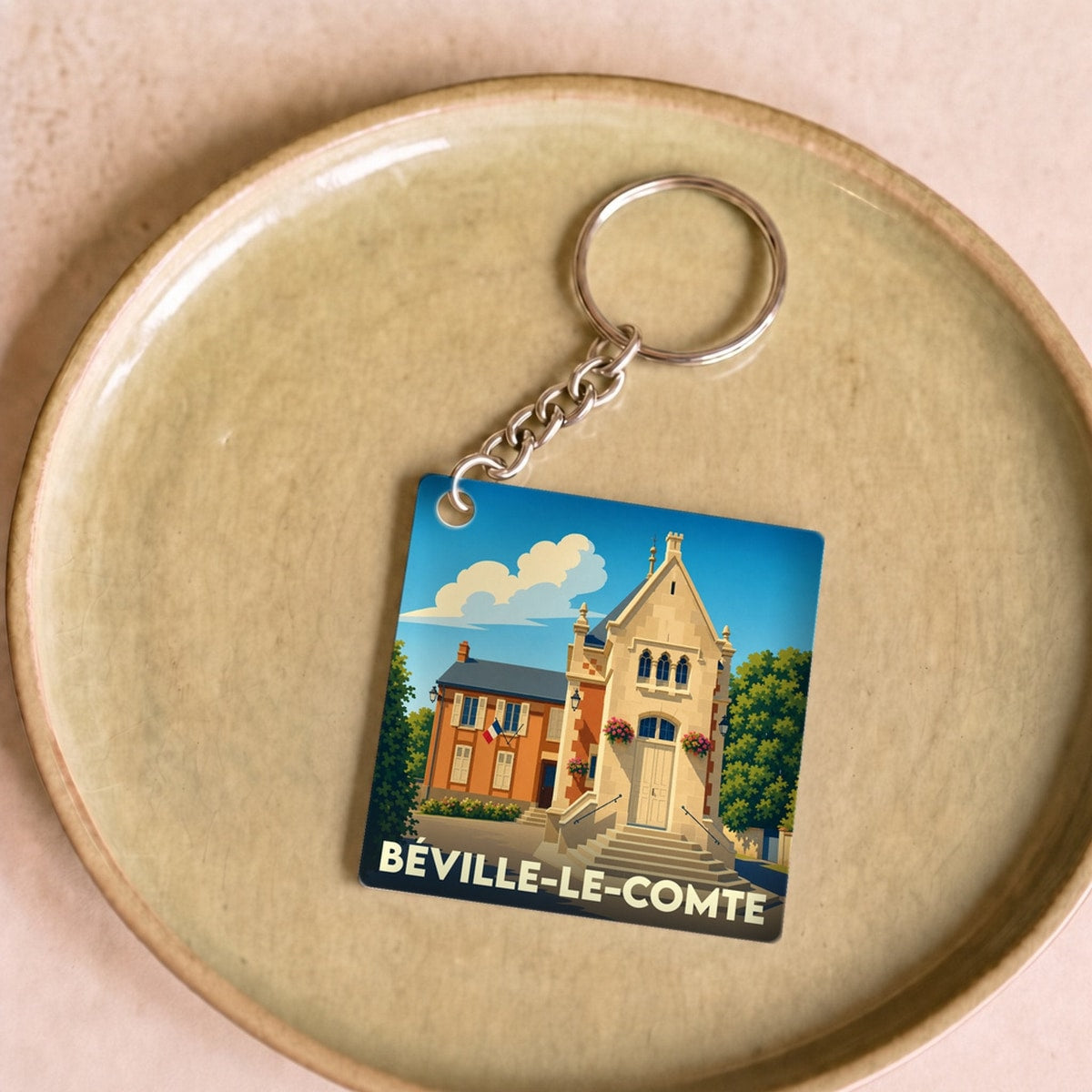Porte-clés souvenir de la ville de Béville-le-Comte avec une illustration stylisée de son patrimoine.