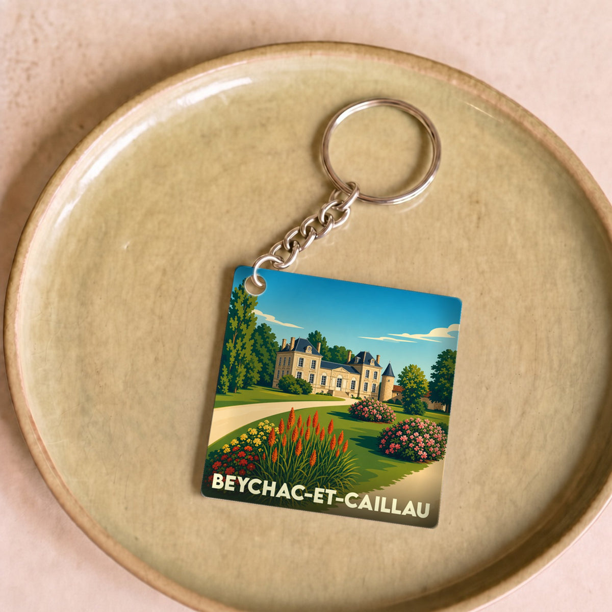 Porte-clés souvenir de la ville de Beychac-et-Caillau avec une illustration stylisée d'un château et de ses jardins.