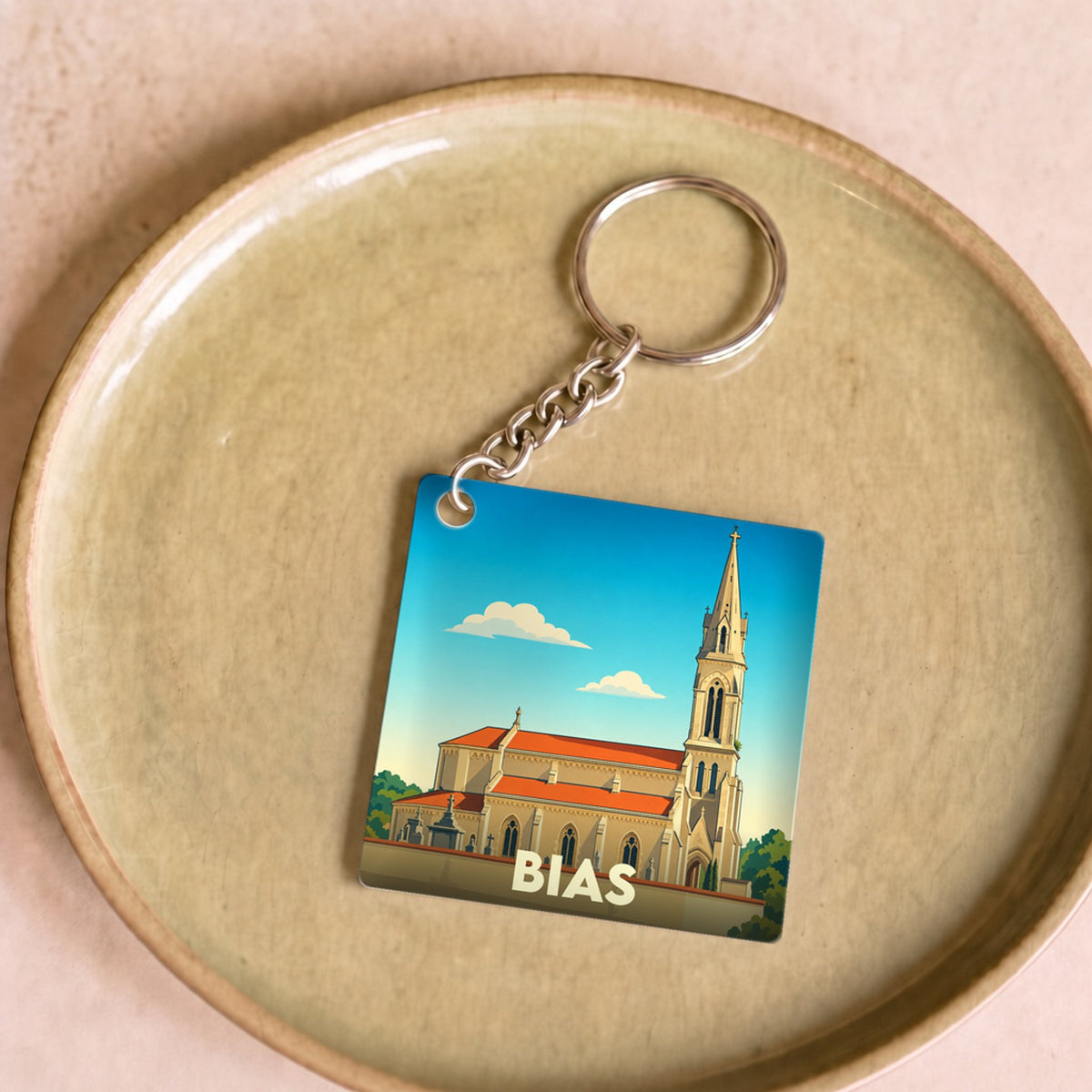Porte-clés souvenir de la ville de Bias avec une illustration stylisée de son église.
