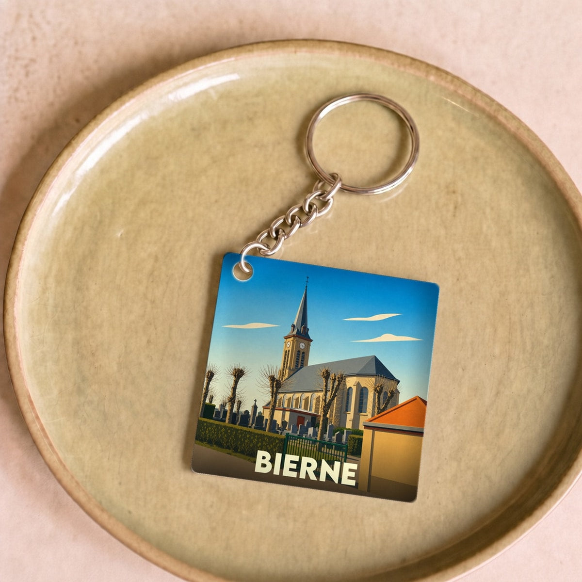 Porte-clés souvenir de la ville de Bierne avec une illustration stylisée de son église.