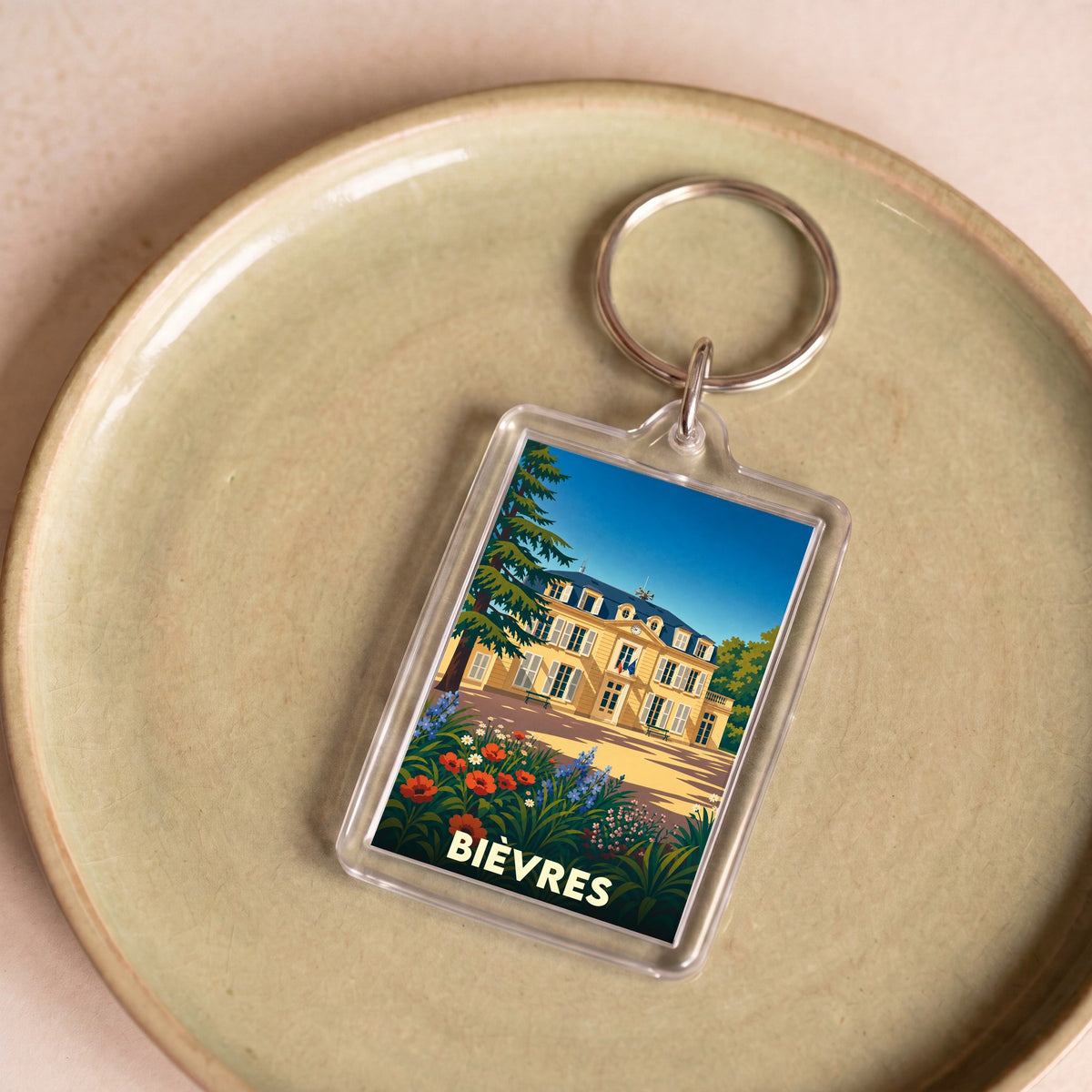 Porte-clés souvenir de la ville de Bièvres avec une illustration stylisée d'un château fleuri.