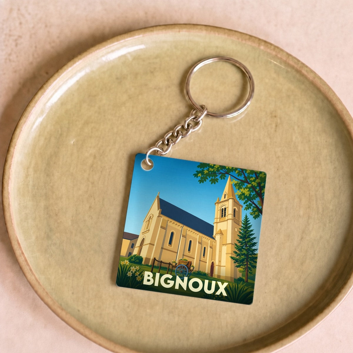 Porte-clés souvenir de la ville de Bignoux avec une illustration stylisée de son église.
