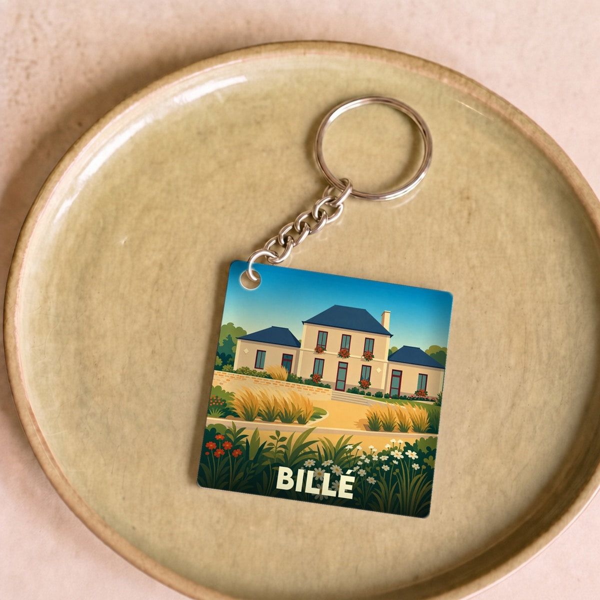 Porte-clés souvenir de la ville de Billé avec une illustration stylisée d'une maison de campagne.