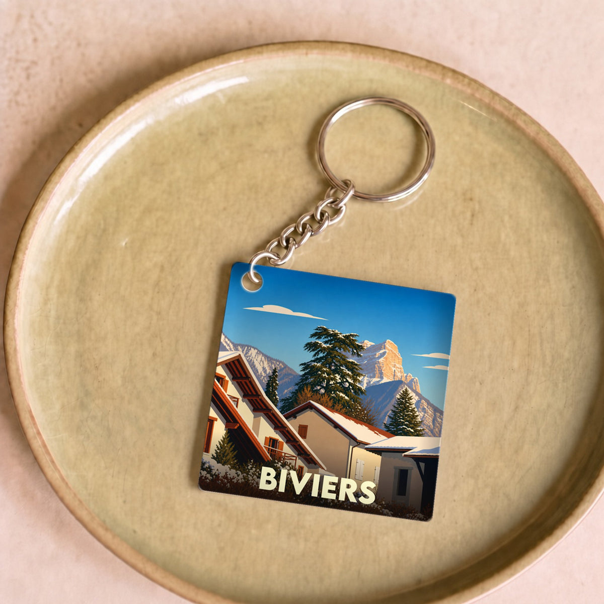 Porte-clés souvenir de la ville de Biviers avec une illustration stylisée de paysages enneigés.