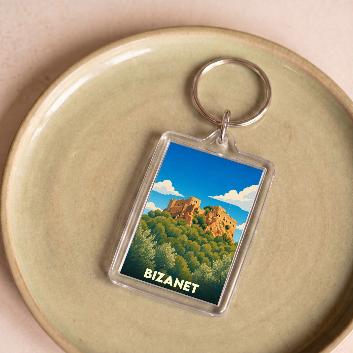 Porte-clés souvenir de la ville de Bizanet avec une illustration stylisée d'un château sur une colline.