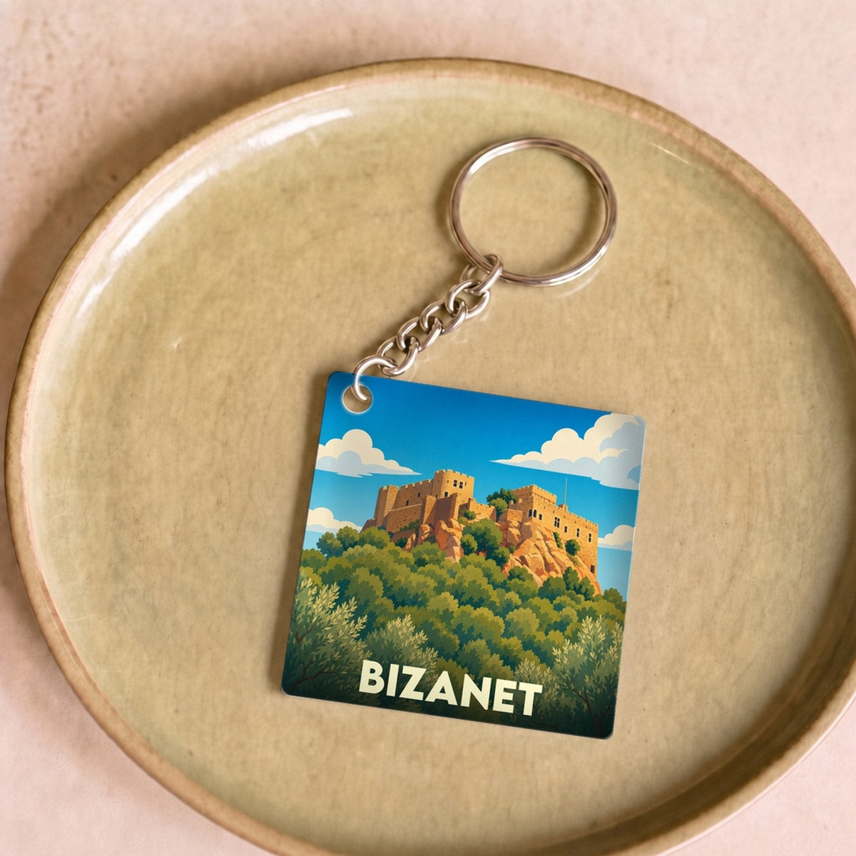Porte-clés souvenir de la ville de Bizanet avec une illustration stylisée d'un château sur une colline.