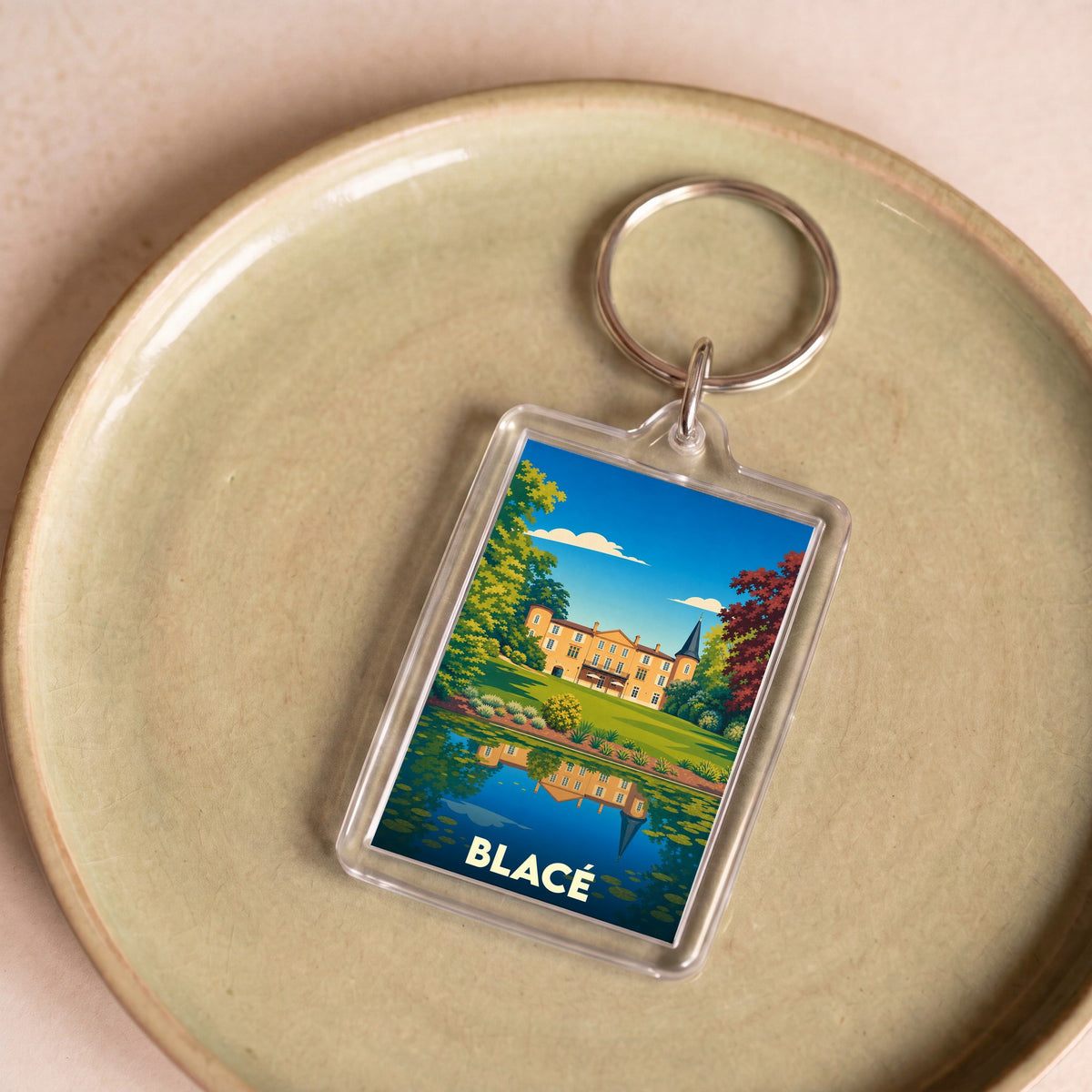 Porte-clés souvenir de la ville de Blacé avec une illustration stylisée d'un château se reflétant dans l'eau.