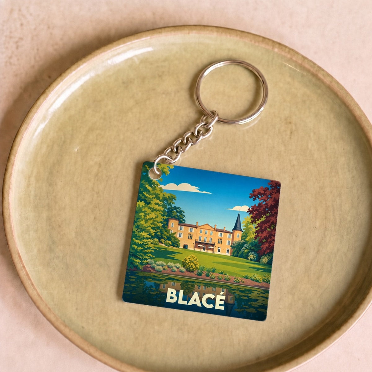 Porte-clés souvenir de la ville de Blacé avec une illustration stylisée d'un château se reflétant dans l'eau.