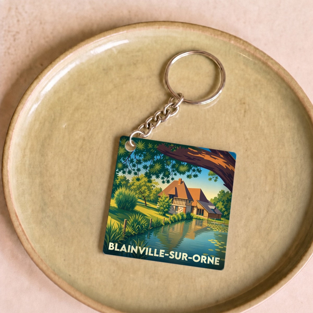 Porte-clés souvenir de la ville de Blainville-sur-Orne avec une illustration stylisée d'une maison au bord de l'eau.