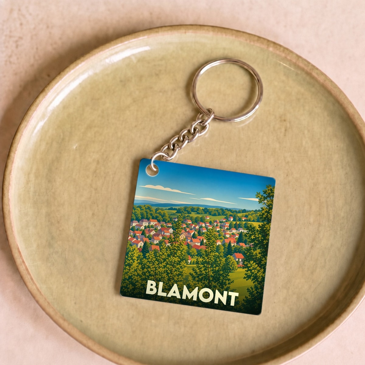 Porte-clés souvenir de la ville de Blamont avec une illustration paysagère stylisée.
