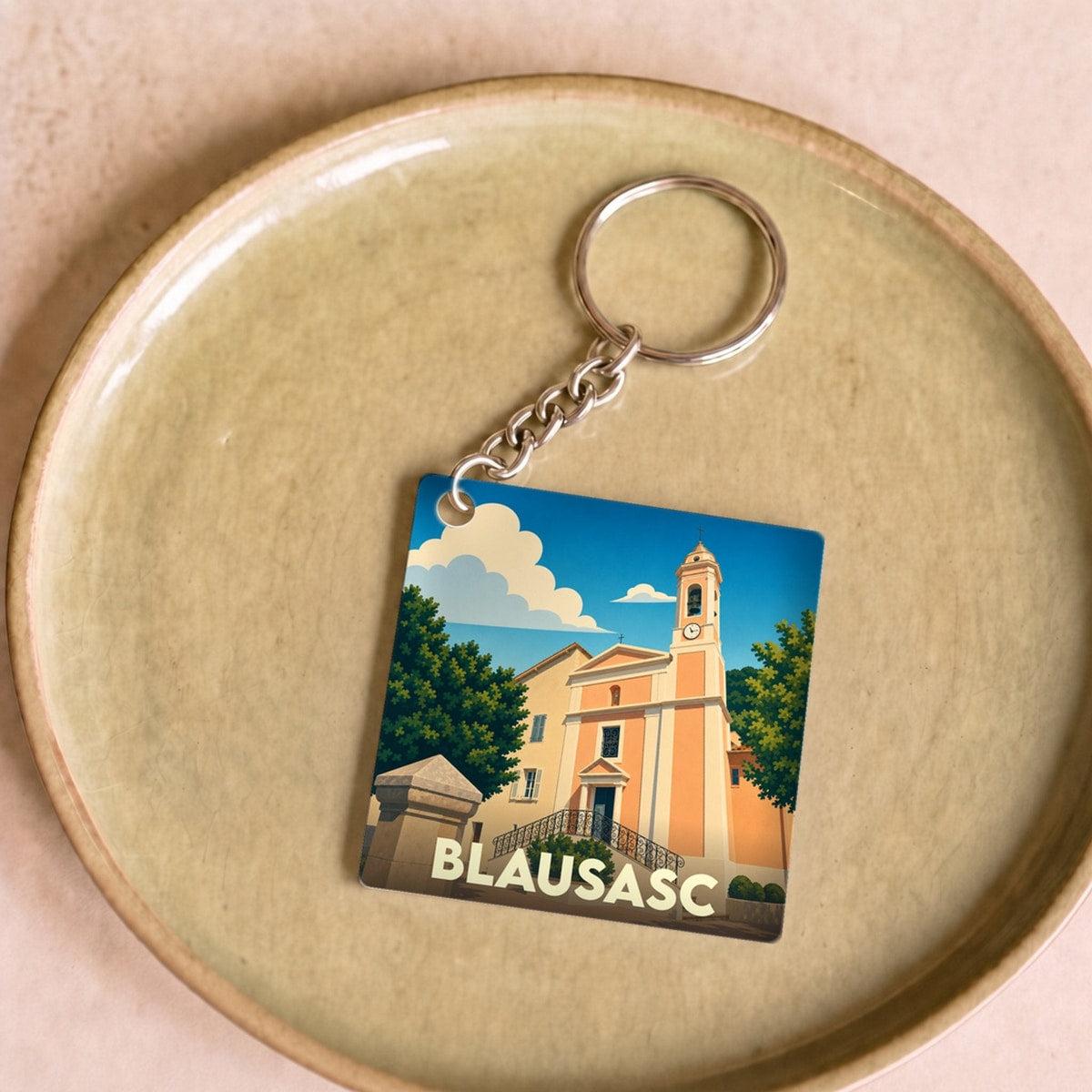 Porte-clés souvenir de la ville de Blausasc avec une illustration stylisée de son église.
