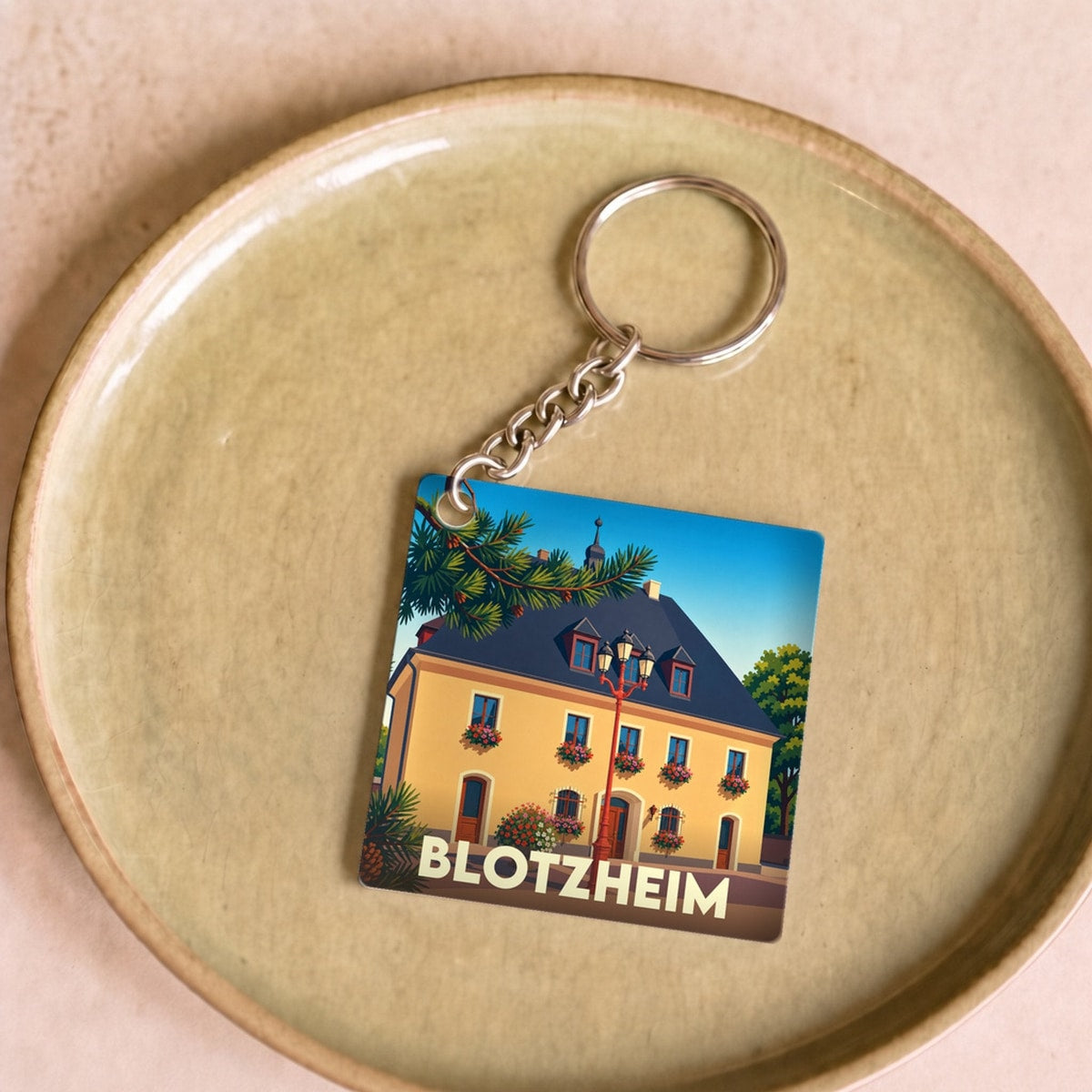 Porte-clés souvenir de la ville de Blotzheim avec une illustration stylisée.