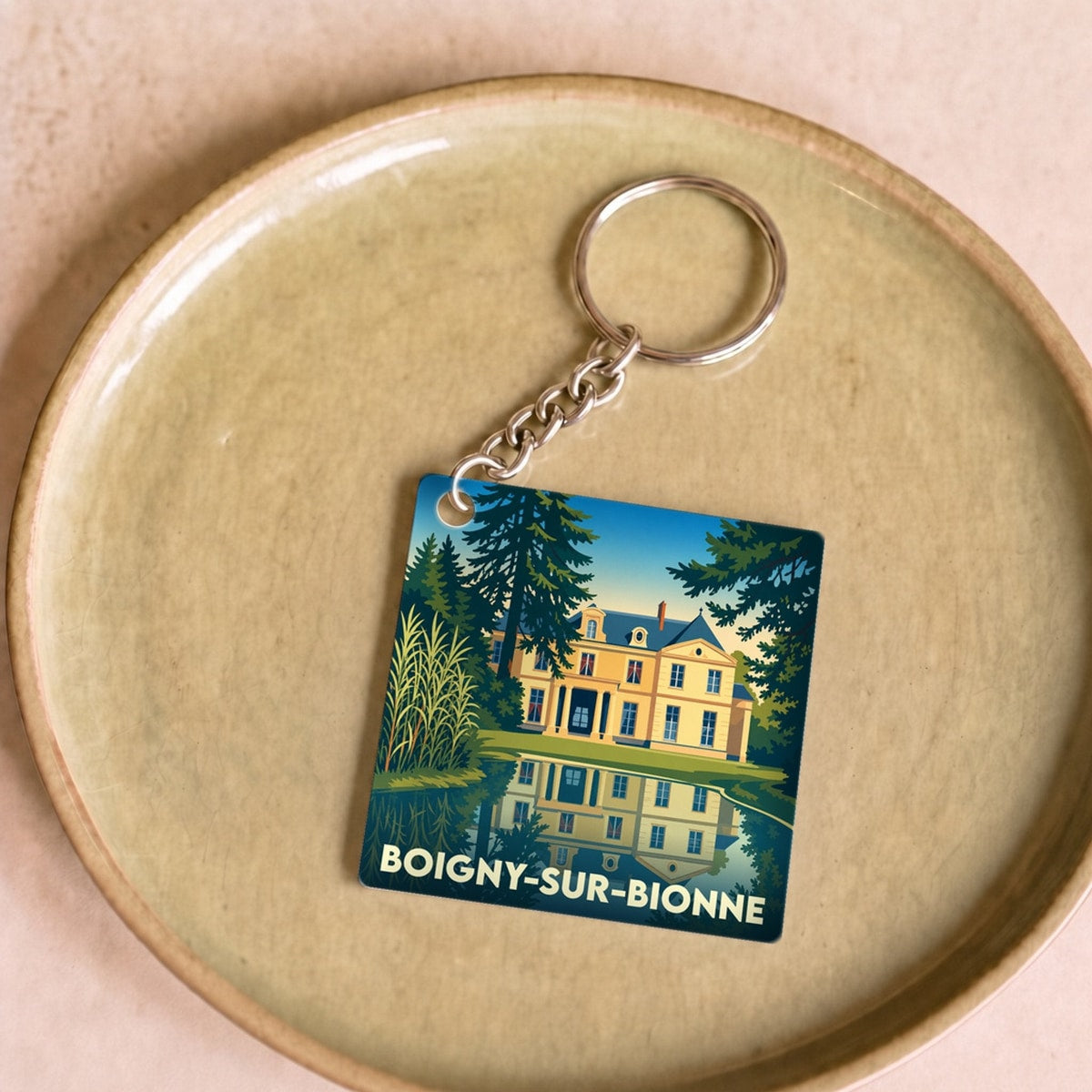 Porte-clés souvenir de la ville de Boigny-sur-Bionne avec une illustration stylisée d'un château se reflétant dans l'eau.