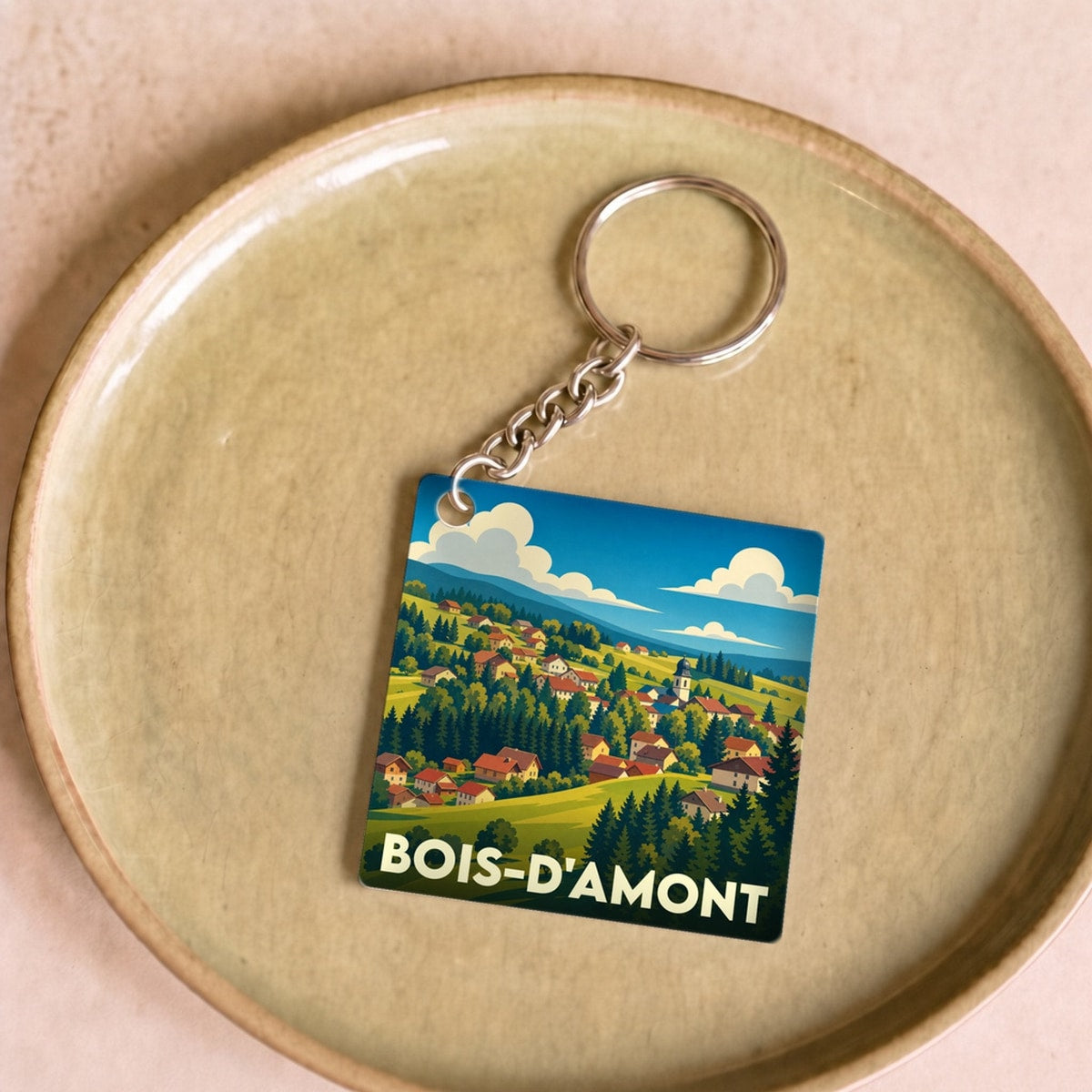 Porte-clés souvenir de la ville de Bois-d'Amont avec une illustration stylisée d'un paysage de montagne.