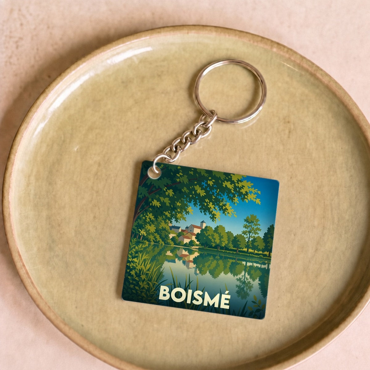 Porte-clés souvenir de la ville de Boismé avec une illustration stylisée d'un paysage au bord de l'eau.
