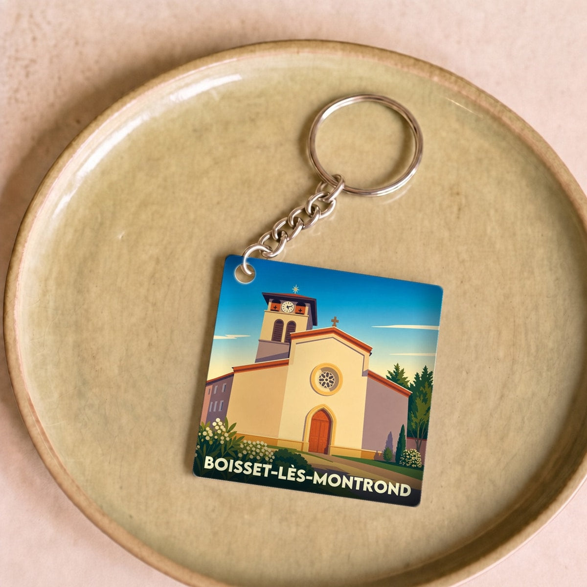 Porte-clés souvenir de la ville de Boisset-lès-Montrond avec une illustration stylisée de son église.