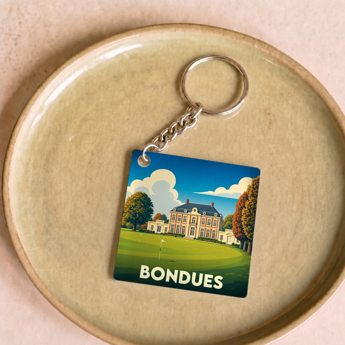 Porte-clés souvenir de la ville de Bondues avec une illustration stylisée d'un château sur un golf.