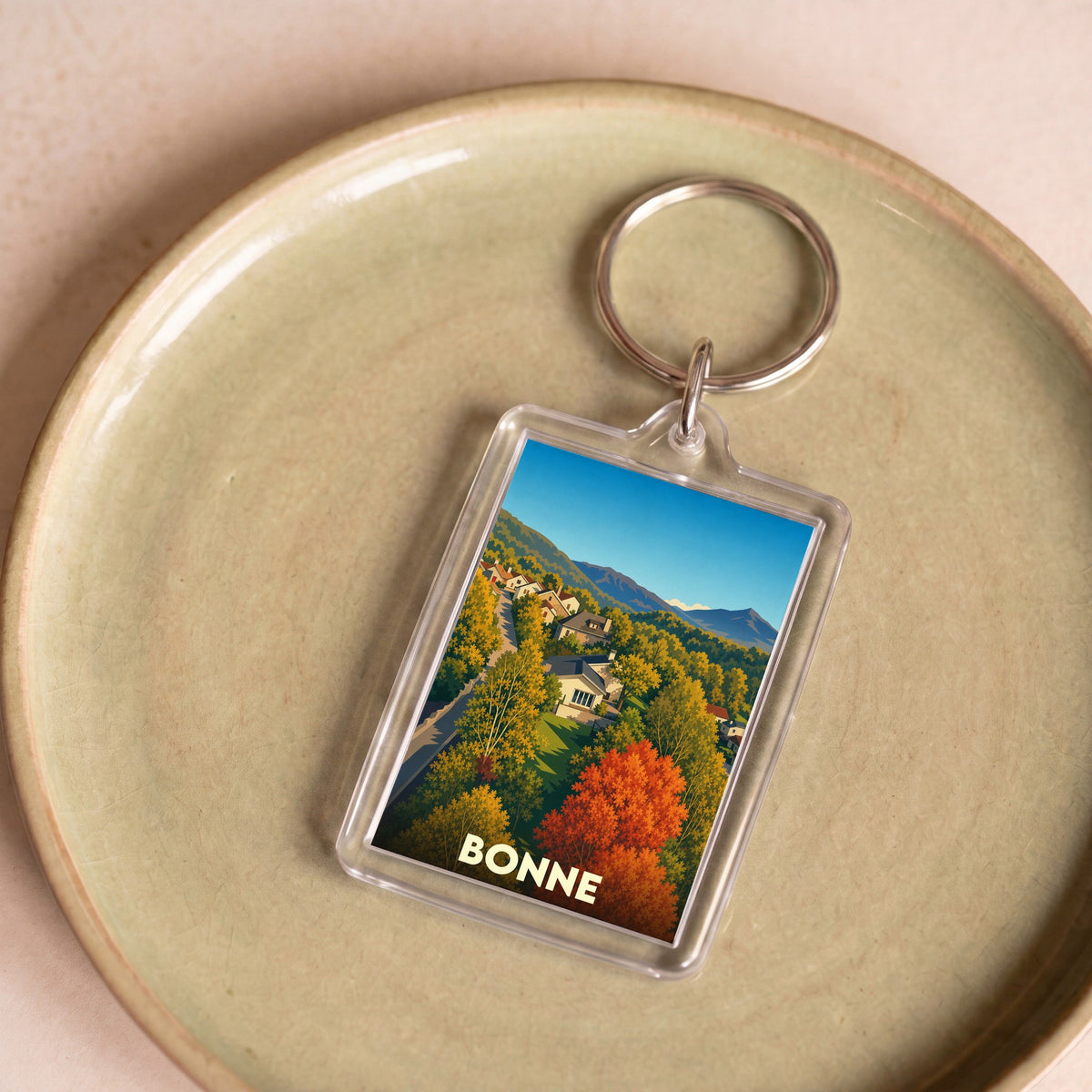 Porte-clés souvenir de la ville de Bonne avec une illustration stylisée d'un paysage d'automne.
