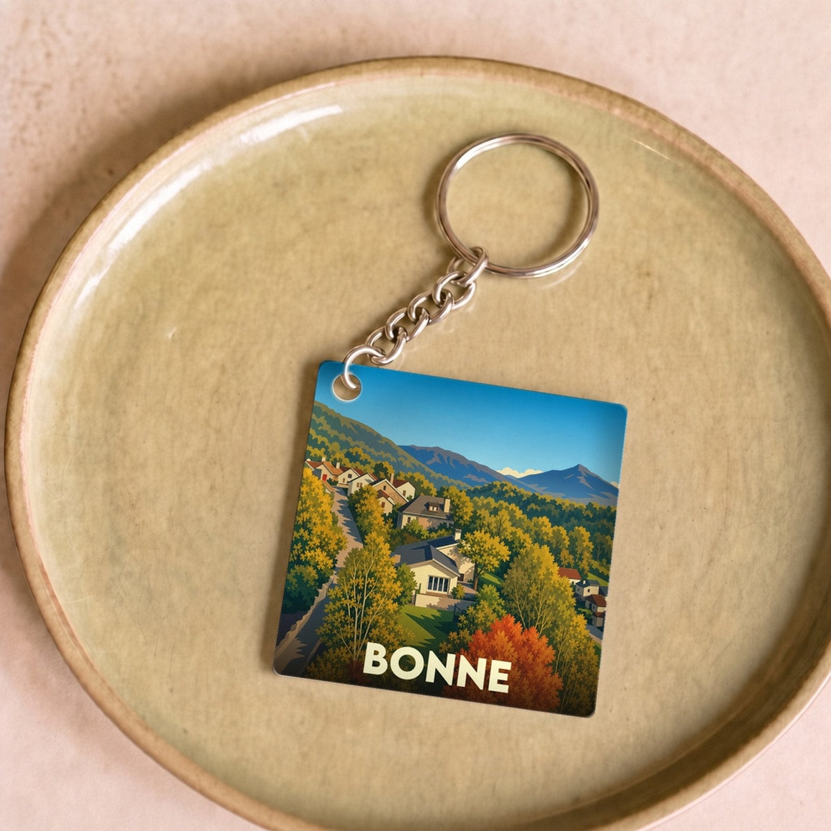 Porte-clés souvenir de la ville de Bonne avec une illustration stylisée d'un paysage d'automne.