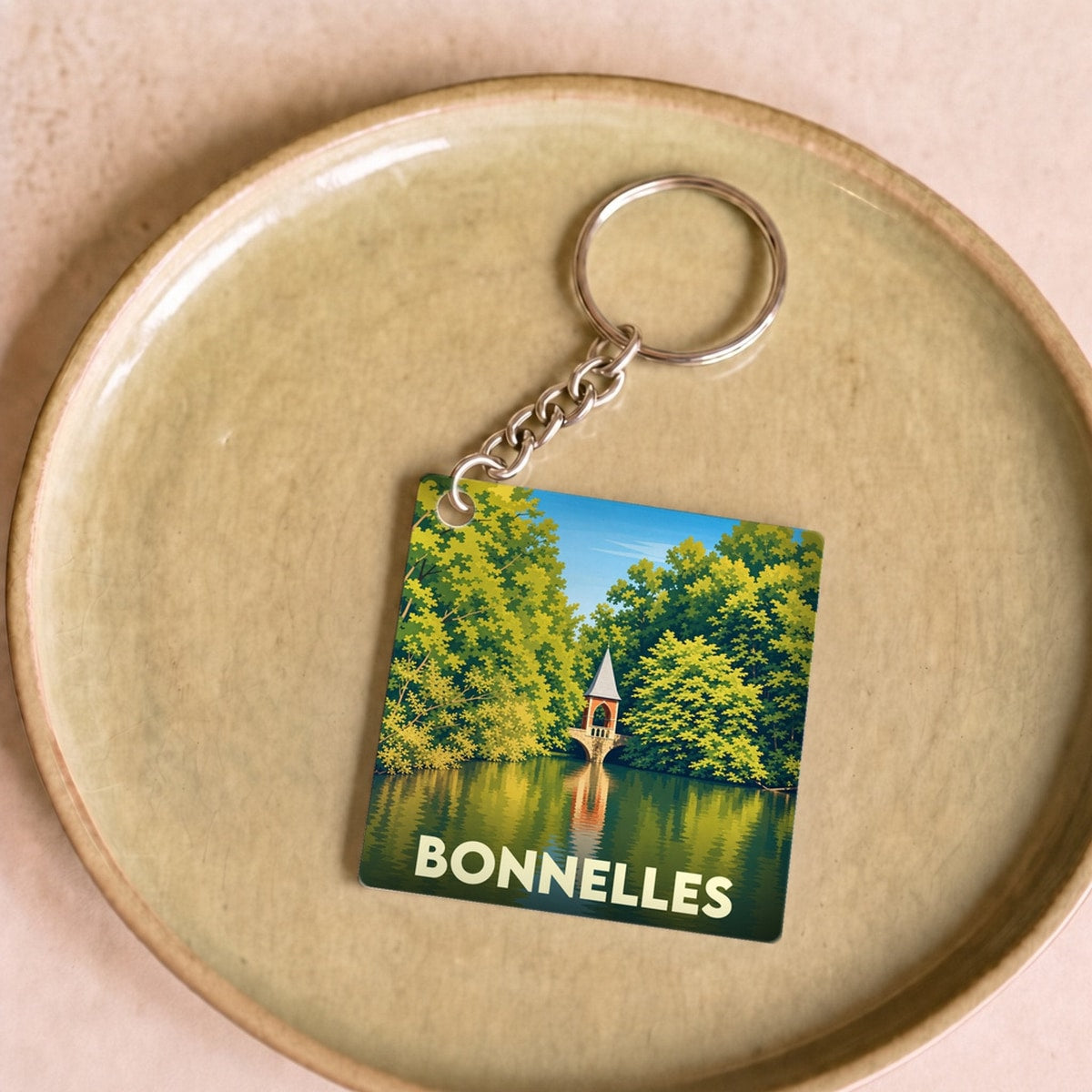 Porte-clés souvenir de la ville de Bonnelles avec une illustration stylisée d'un pavillon au bord de l'eau.