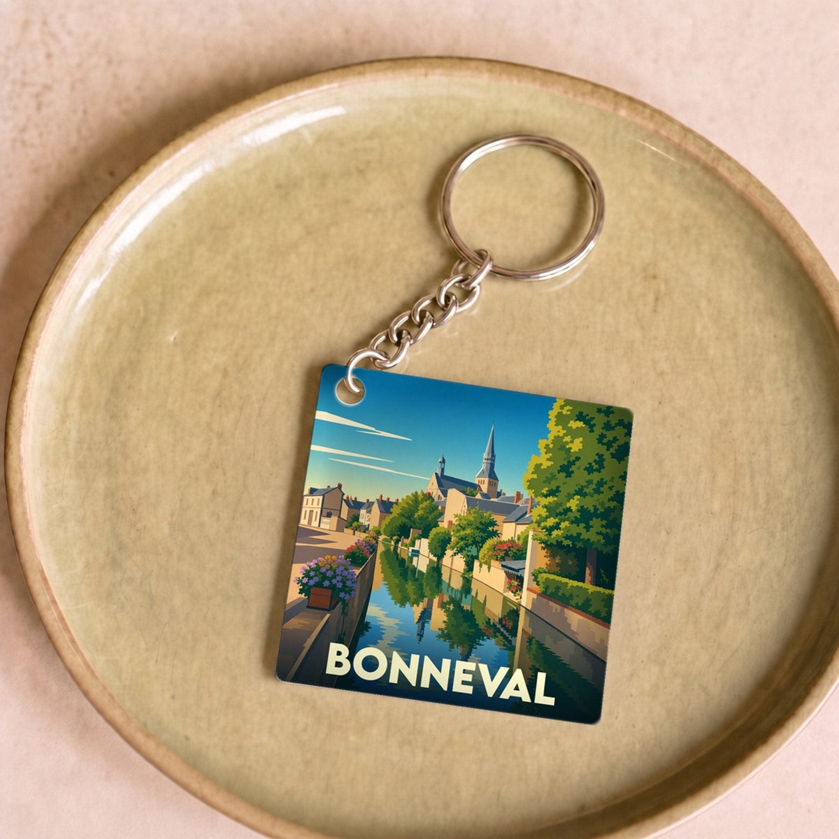 Porte-clés souvenir de la ville de Bonneval avec une illustration stylisée d'un canal et de son église.