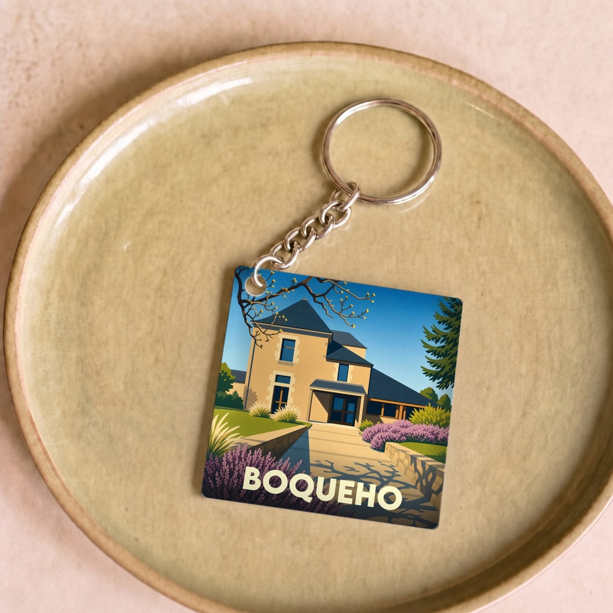 Porte-clés souvenir de la ville de Boqueho avec une illustration stylisée d'une maison bretonne.