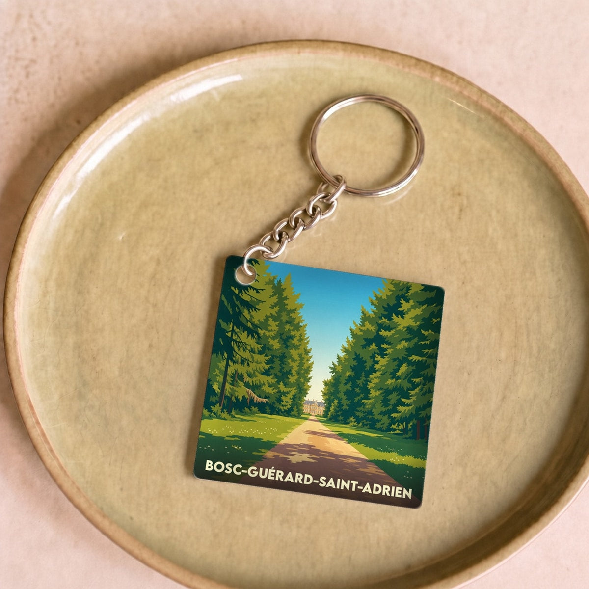 Porte-clés souvenir de la ville de Bosc-Guérard-Saint-Adrien avec une illustration stylisée d'un chemin forestier.
